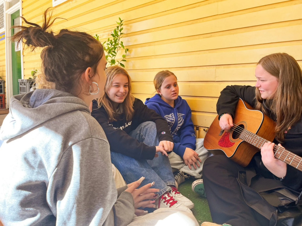 Group of four youths singing and playing guitar during vocational training at Fairbridge College