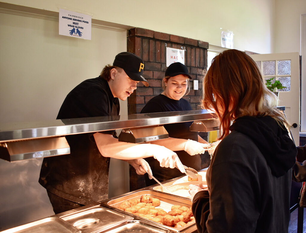 Two people enjoy serving dishes at a buffet, demonstrating essential life skills in food preparation