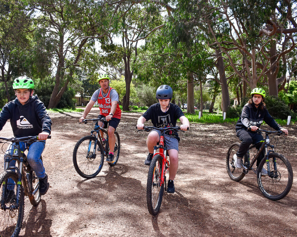 Multiple students biking outdoors with a mentor